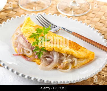 Delicious egg omelette remplie d'oignons frits sur une assiette. Le petit-déjeuner ou le brunch. Banque D'Images