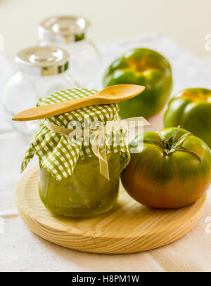 Chutney de tomates vertes dans un pot sur une surface en bois Banque D'Images