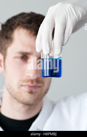 Chimiste tenant une tasse de mesure remplie d'un liquide bleu Banque D'Images