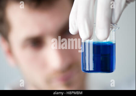 Chimiste tenant une tasse de mesure remplie d'un liquide bleu Banque D'Images