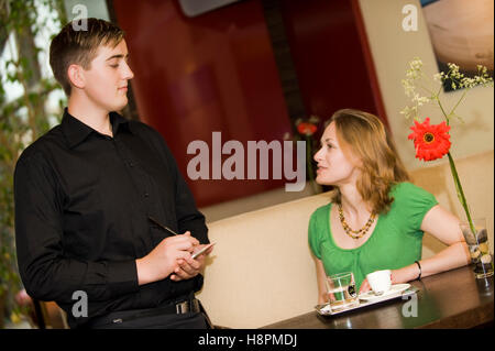 Waiter serving young woman in a cafe Banque D'Images