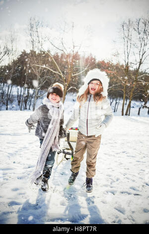 Image composite de frère et sœur jouant à traineau sur la neige domaine Banque D'Images