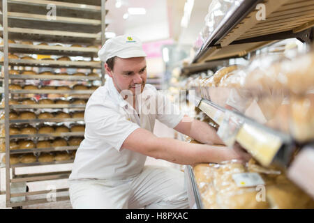 Intérieur d'un supermarché Morrisons. Un homme empile les étagères avec du pain frais Banque D'Images