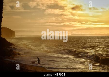 West Bay, Dorset, UK. 16 Nov, 2016. Météo britannique. Un matin tôt dog walker jouit du lever du soleil sur la plage de West Bay sur ce qui promet d'être une journée ensoleillée dans le sud ouest. Crédit : Tom Jura/Alamy Live News Banque D'Images