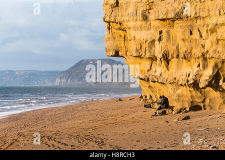 Burton Bradstock, Dorset, UK. 16 novembre 2016. Deux femmes assises sous un dangereux surplombant l'article de falaise à la plage de ruche à Burton Bradstock à Dorset apparemment inconscients du danger au-dessus d'eux. L'emblématique golden Cliffs at Burton Bradstock sont belle mais dangereuse, car il y a de nombreux glissements de terrain au cours de l'année qui a conduit à un décès en 2012, ce qui conduit les autorités à mettre en garde les gens de ne pas s'asseoir ou de marcher sous les falaises. Photo : Graham Hunt/Alamy Live News Banque D'Images