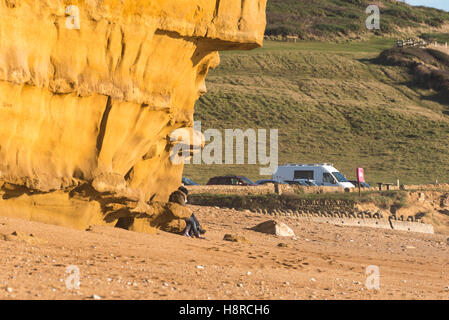 Burton Bradstock, Dorset, UK. 16 novembre 2016. Deux femmes assises sous un dangereux surplombant l'article de falaise à la plage de ruche à Burton Bradstock à Dorset apparemment inconscients du danger au-dessus d'eux. L'emblématique golden Cliffs at Burton Bradstock sont belle mais dangereuse, car il y a de nombreux glissements de terrain au cours de l'année qui a conduit à un décès en 2012, ce qui conduit les autorités à mettre en garde les gens de ne pas s'asseoir ou de marcher sous les falaises. Photo : Graham Hunt/Alamy Live News Banque D'Images