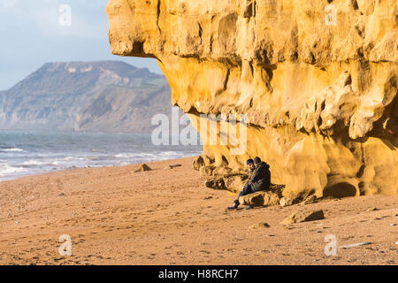 Burton Bradstock, Dorset, UK. 16 novembre 2016. Deux femmes assises sous un dangereux surplombant l'article de falaise à la plage de ruche à Burton Bradstock à Dorset apparemment inconscients du danger au-dessus d'eux. L'emblématique golden Cliffs at Burton Bradstock sont belle mais dangereuse, car il y a de nombreux glissements de terrain au cours de l'année qui a conduit à un décès en 2012, ce qui conduit les autorités à mettre en garde les gens de ne pas s'asseoir ou de marcher sous les falaises. Photo : Graham Hunt/Alamy Live News Banque D'Images