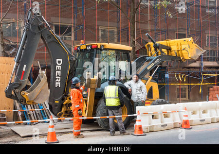 John Deere 410J avec les travailleurs de la construction sur un chantier à New York City Banque D'Images