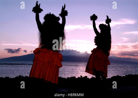 Maui, Hawaï, États-Unis. Deux femmes interprétant la danse hula hawaïenne traditionnelle au coucher du soleil sur la plage, face à l'océan Pacifique. Banque D'Images