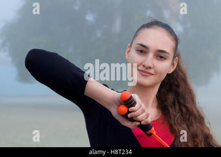 Jolie jeune femme sportive remise en forme slim streching avec corde d'exercice en plein air d'entraînement pendant l'entraînement Banque D'Images