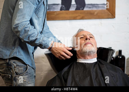 Le vieux Nice man waiting pour laver les cheveux dans un salon de barbier Banque D'Images