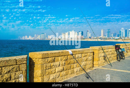Les cannes à pêche sur la promenade de la ville avec vue sur la ville de Tel Aviv, Israël en arrière plan. Banque D'Images