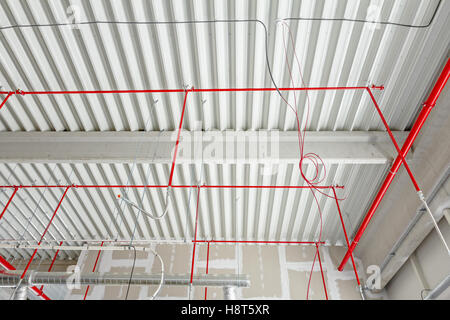 Avec un système d'extinction automatique tuyaux rouge est placé à suspendu au plafond à l'intérieur d'un nouveau bâtiment. Banque D'Images