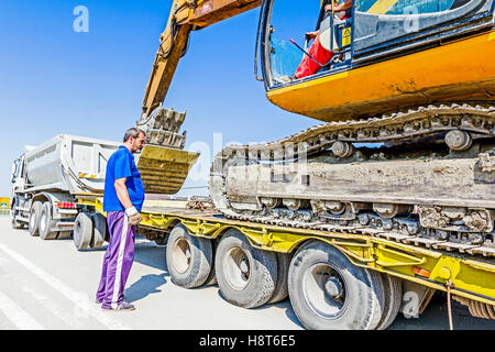 Zrenjanin, en Voïvodine, Serbie - 27 août 2015 : il monte sur l'excavatrice remorque plate-forme basse sur rampe arrière, transportant deux b Banque D'Images