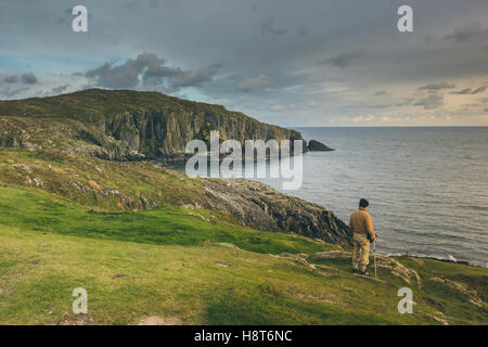 Un homme debout au bord d'une falaise surplombant l'océan avec l'horizon à l'arrière-plan. Banque D'Images