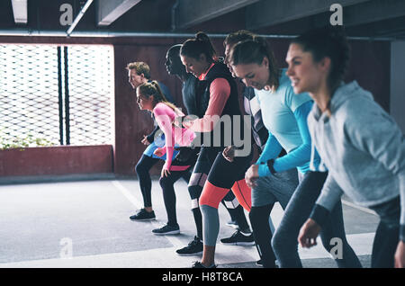 Groupe de jeunes amis divers la queue pour une exécution au sein d'un grand parc de stationnement commercial dans un concept de santé et de remise en forme Banque D'Images