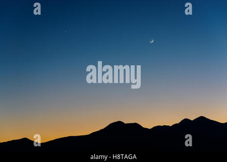 Lune croissante, Vénus (à gauche) et Saturne (milieu) au crépuscule. Silhouette de montagnes près de Katmandou au Népal. Banque D'Images