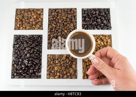 Une femme ayant atteint tasse de café sur le dessus de grains de café Banque D'Images