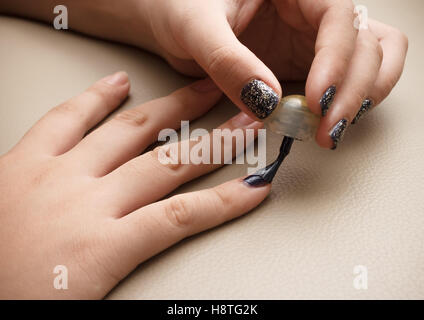 Quelqu'un d'appliquer délicatement le vernis à ongles de couleur noire à l'aide d'un pinceau pour faire un très beau nail art. Banque D'Images