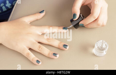 Quelqu'un d'appliquer doucement la couleur transparente à l'aide d'une brosse à ongles pour faire un très beau nail art. Banque D'Images