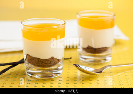 New York Cheesecake à la mangue dans les verres sur table jaune Banque D'Images