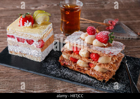 Fraises Crème mille feuille glaçage sucré dessert sur pierre noire Banque D'Images