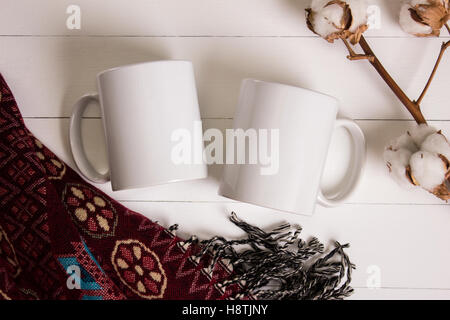 Deux tasses, blanc paire de tasses, immersive. Atmosphère confortable, fond de bois, du coton et de la laine pour l'hiver décoration cadeaux. Banque D'Images