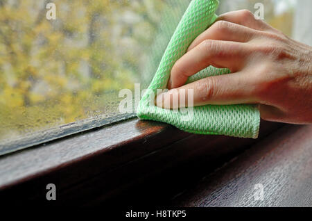 Woman cleaning la condensation de l'eau sur la fenêtre Banque D'Images