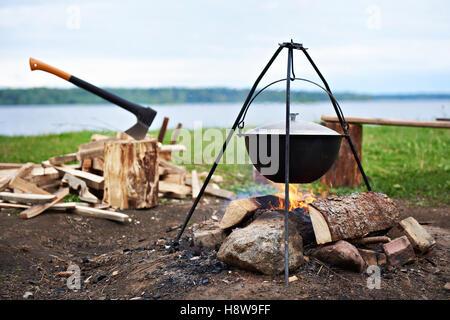 Randonnées paysage avec bonfire, pot et une hache Banque D'Images