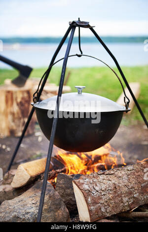 Randonnées paysage avec bonfire, pot et une hache Banque D'Images