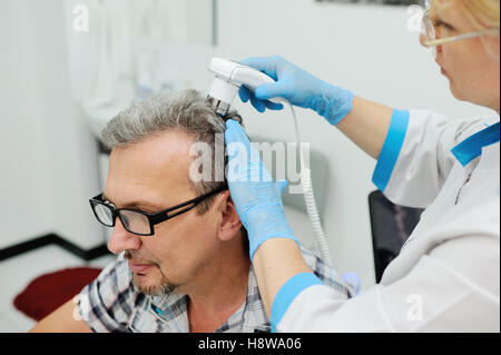 Diagnostics cheveux et le cuir chevelu. Trihoskopiya. Médecin patient examiner un appareil spécial cheveux hommes Banque D'Images