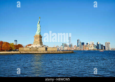 Temps d'automne de la statue de la liberté sur socle en face de Manhattan. Banque D'Images