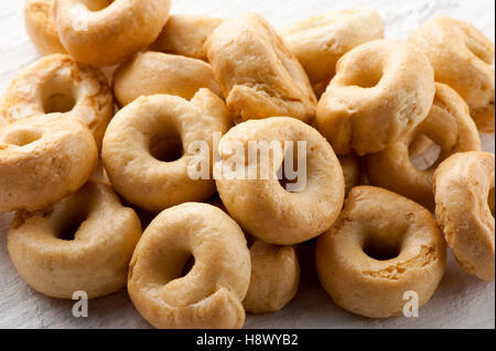Pile de biscuits croquants taralli italiens pour une savoureuse collation doigt dans un plan rapproché sur un tableau blanc Banque D'Images