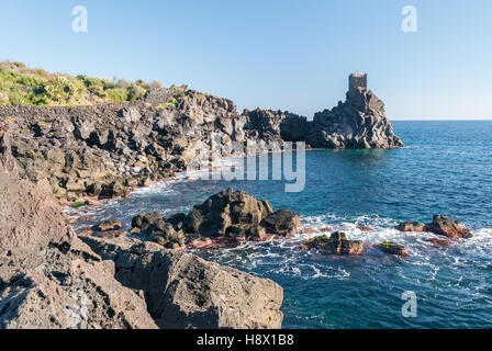 La côte rocheuse de la falaise de lave près de Taormina (Sicile), avec un tour de garde dans l'arrière-plan Banque D'Images