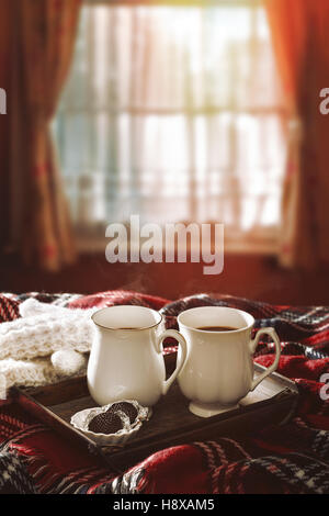 Chocolat chaud sur un tapis en tartan avec winter sunshine filtrant à travers la fenêtre Banque D'Images