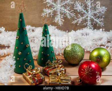Sapins de Noël feutre avec jouets, cadeaux et les flocons de neige sur un fond de bois Banque D'Images