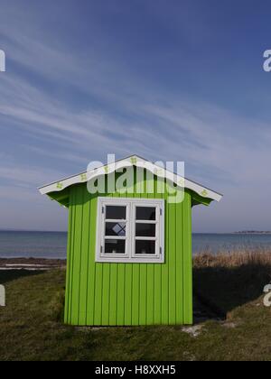 Un joli lime-green beach hut avec toit blanc et le cadre de la fenêtre sur un fond de mer bleu et bleu ciel. Banque D'Images