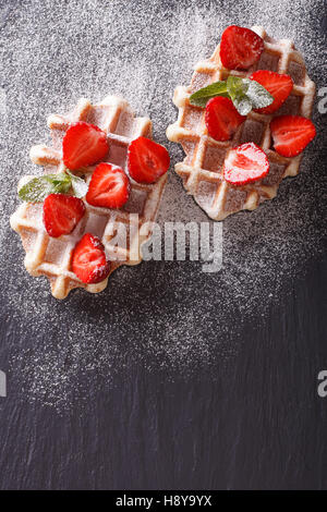 Délicieux dessert : gaufres aux fraises, sucre en poudre gros plan sur l'ardoise. vertical Vue de dessus Banque D'Images
