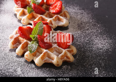 Délicieux dessert : gaufres aux fraises, sucre en poudre gros plan sur l'horizontale de l'ardoise. Banque D'Images