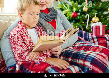 Adorable enfant lire des histoires dans le livre avec sa grand-mère Banque D'Images
