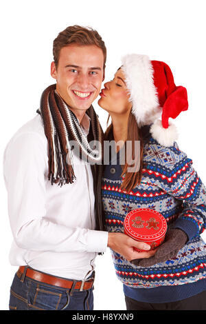Girl in santa hat kissing boy, fond blanc, studio shot Banque D'Images