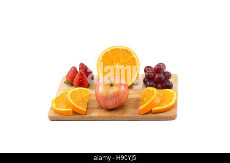 Les raisins rouges avec une demi-orange et coupes, fraises, bleuets et apple sur planche de bois isolé sur fond blanc Banque D'Images