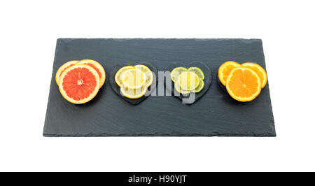 Fabrication d'agrumes orange, pamplemousse rose, de citron et de lime sur black slate board isolé sur fond blanc Banque D'Images