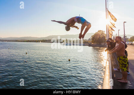 Jeune homme sautant d'QUAIBRUCKE PONT DANS LE LAC DE ZURICH, ZURICH, SUISSE Banque D'Images