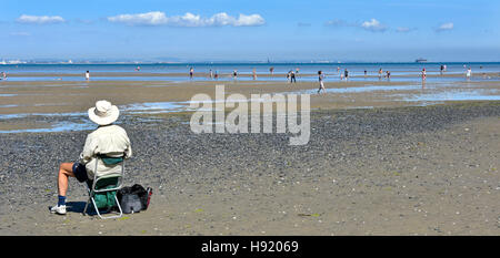 Plus Senior citizen homme vue arrière en vacances siégeant seul Ryde, Isle of Wight Angleterre UK Holiday Beach à marée basse vue sur mer pagaie personnes Solent Banque D'Images