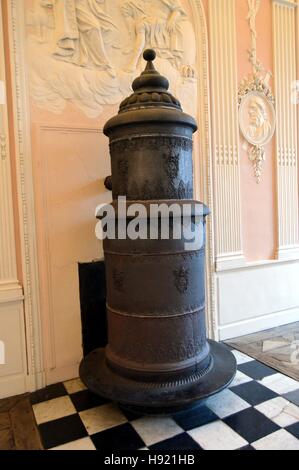 Ancien poêle à bois en fonte et de la colonne en face d'un mur rose Banque D'Images