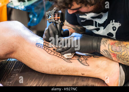 Un homme d'être tatoué sur sa jambe à la Convention de Tatouage de Brighton. Banque D'Images