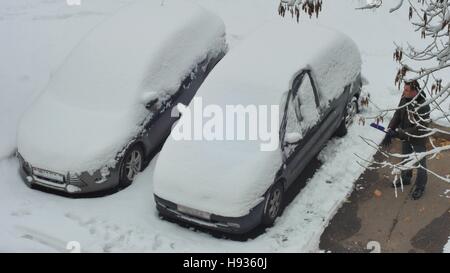 Un homme efface la neige de la voiture le matin après les chutes de neige Banque D'Images