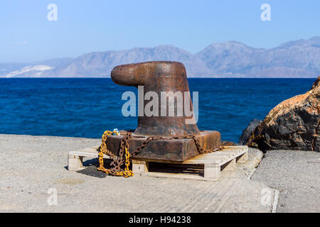 Rusty bitt avec une chaîne sur la couchette. Dans le fond de la mer et les montagnes. Banque D'Images