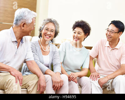 Deux heureux et active senior asian des couples sitting on couch chatting smiling Banque D'Images